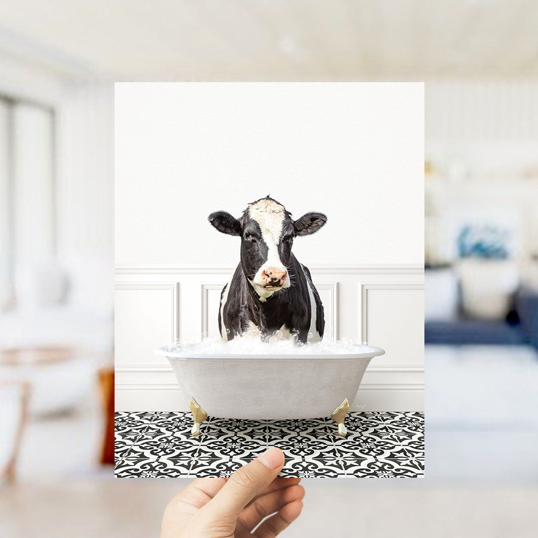 A black and white cow is sitting in a white bathtub filled with water, creating a whimsical and humorous scene.