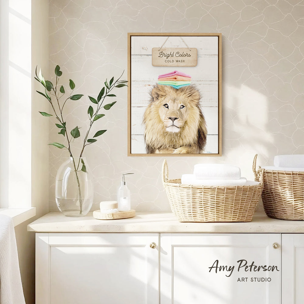 a framed picture of a lion on a wall, with a wicker basket and a vase of leaves on a counter below it.