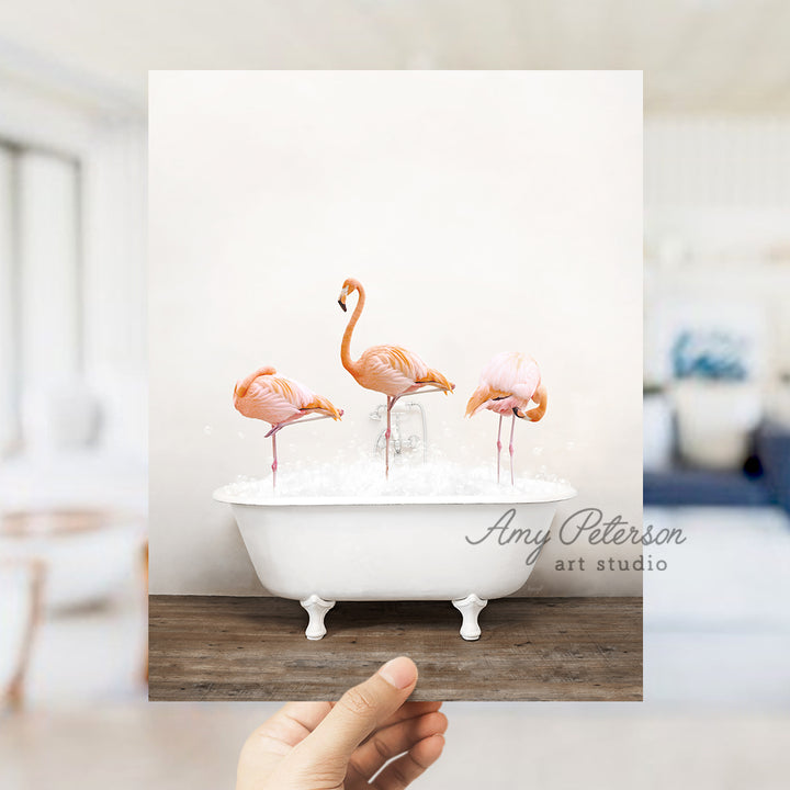 a person holding up a photo of three flamingos in a bathtub