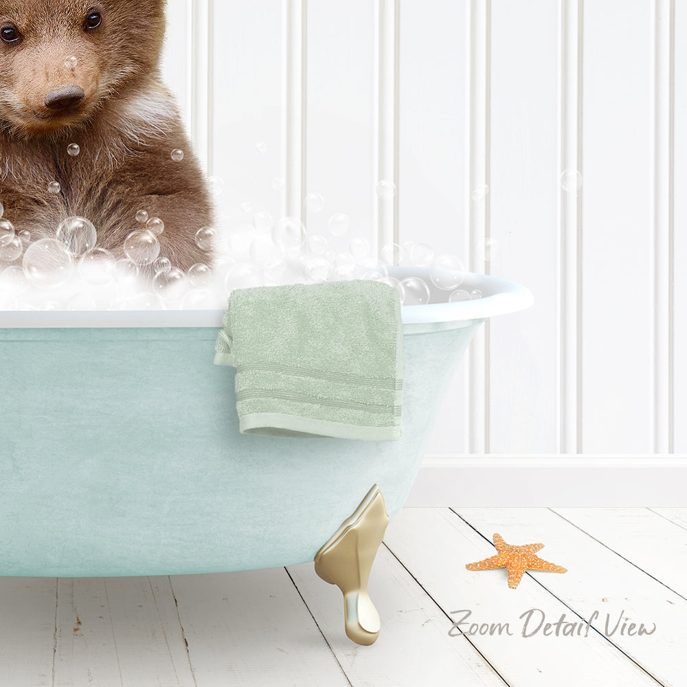 A brown bear is sitting in a light blue bathtub filled with bubbles, with a green towel and a starfish nearby.