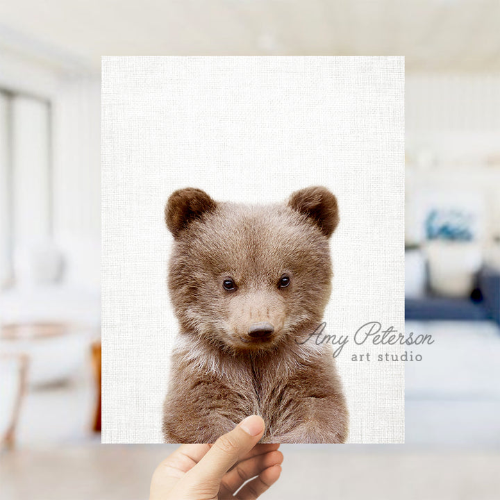 a person holding up a picture of a brown bear