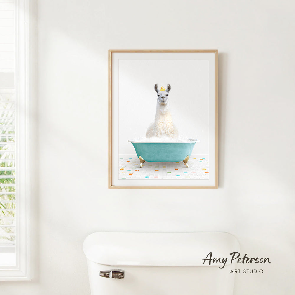 A framed image of a white llama sitting in a blue bathtub, with a white toilet and a window in the background.