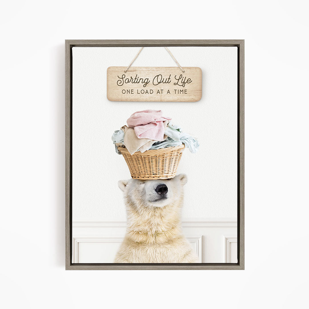 A polar bear balancing a basket of laundry on its head, with a sign above that reads "Sorting Out Life One Load at a Time".