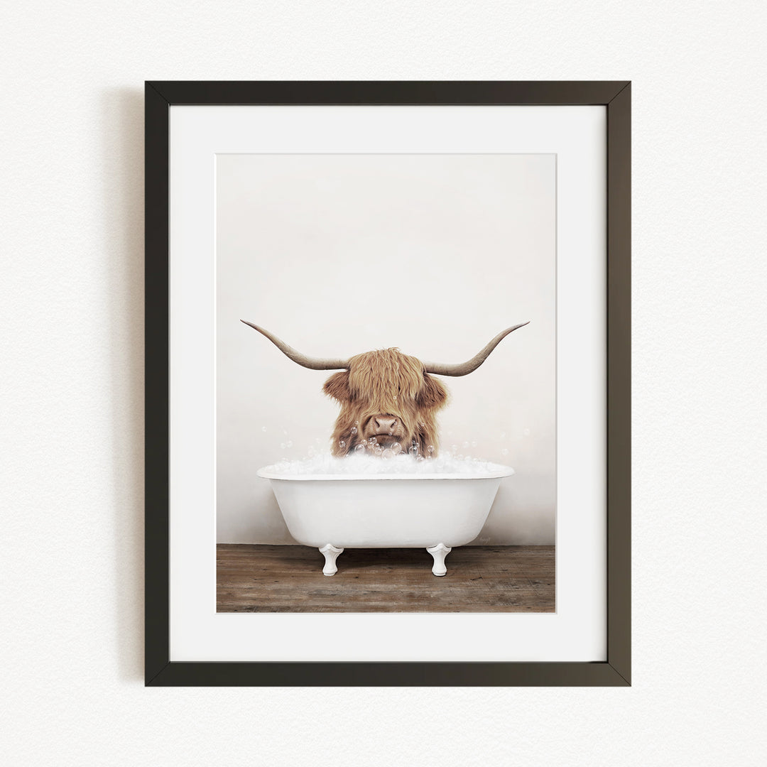 A Highland cow with long horns is sitting in a white bathtub, appearing to enjoy the bath.