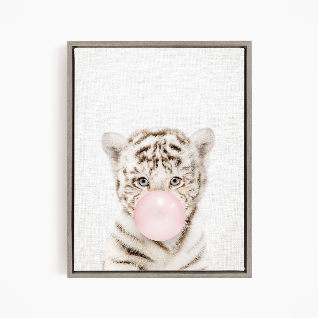 A young tiger cub blowing a bubble with a pink bubble gum bubble.