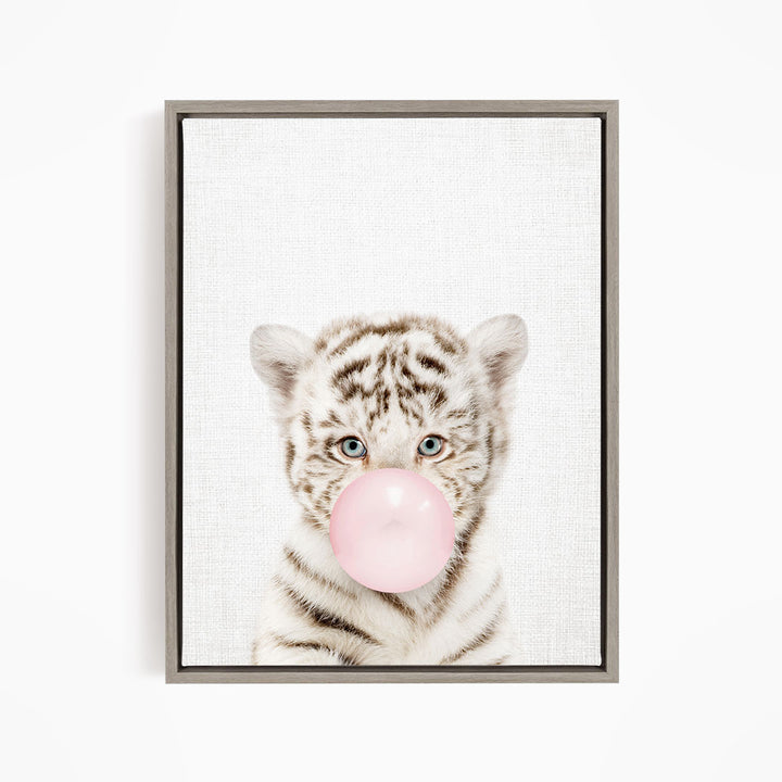 A young tiger cub blowing a bubble with a pink bubble gum bubble.