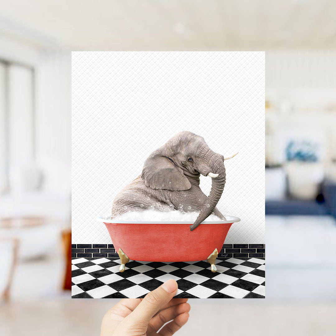 A hand holds up a framed image of an elephant sitting in a red bathtub filled with bubbles, surrounded by a black and white checkered floor.