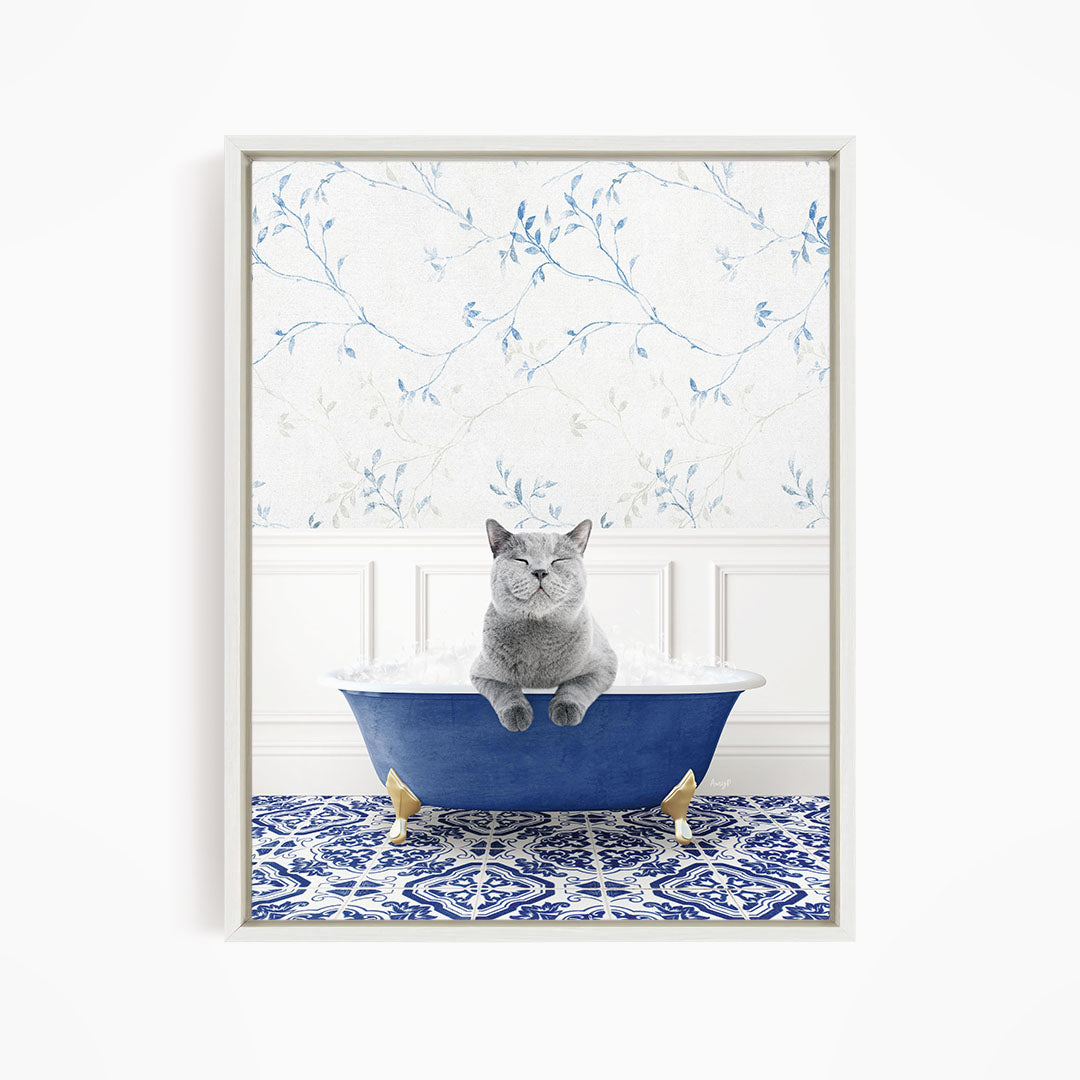 A gray cat sitting in a blue bathtub, with a patterned tile floor and a floral wallpaper in the background.