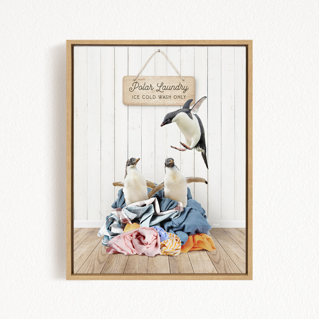 A framed image depicting three penguins standing on a pile of clothes, with a sign that reads "Polar Laundry" and "Ice Cold Wash Only" hanging on a white wall.