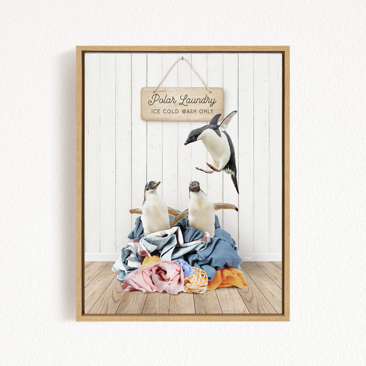 A framed image depicting three penguins standing on a pile of clothes, with a sign that reads "Polar Laundry" and "Ice Cold Wash Only" hanging on a white wall.