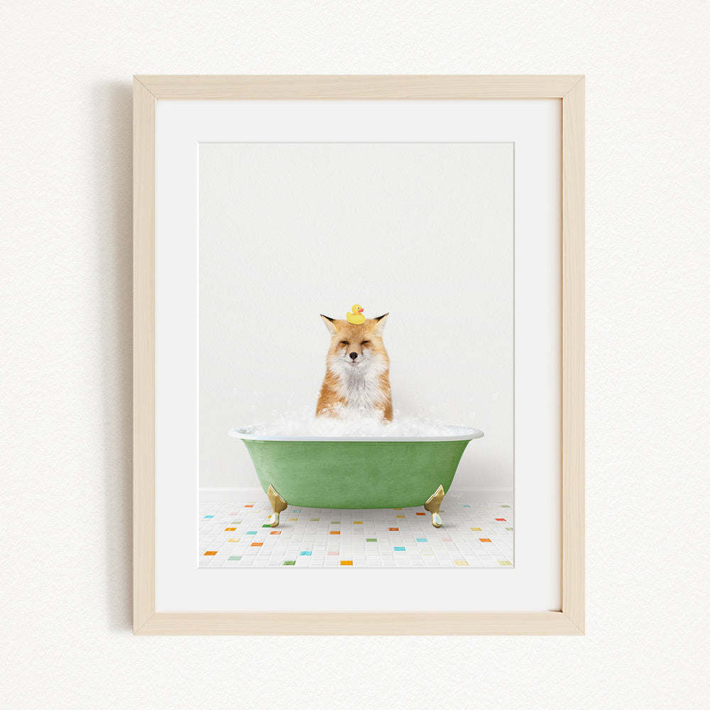 A fox is sitting in a green bathtub filled with bubbles, with a yellow rubber duck perched on its head.