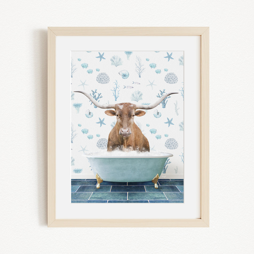 A framed image depicting a brown cow with large horns sitting in a bathtub filled with bubbles, surrounded by a blue and white ocean-themed background.