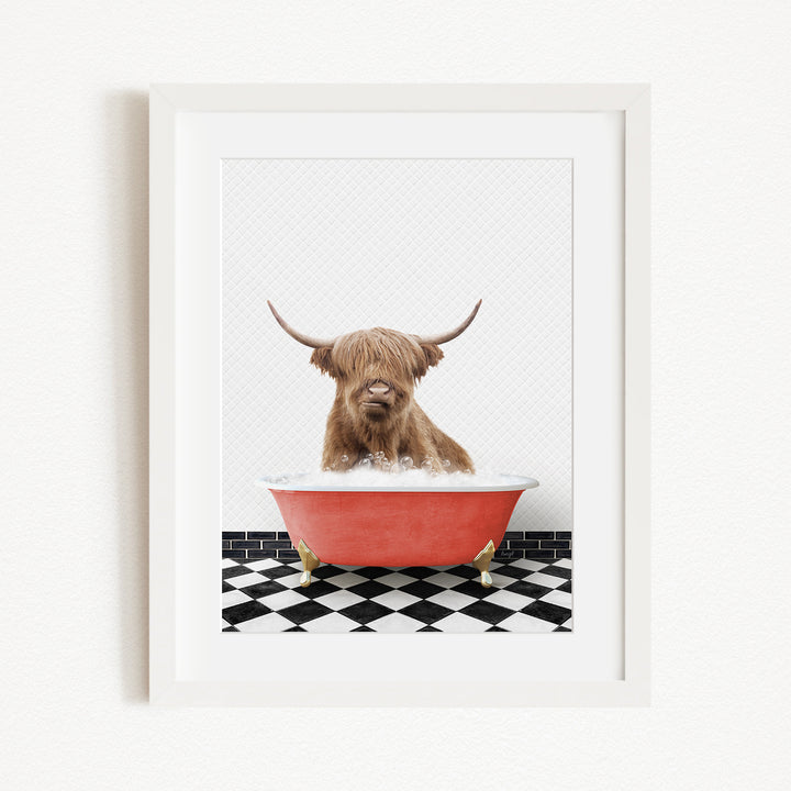 A brown cow with long horns is sitting in a red bathtub on a black and white checkered floor.