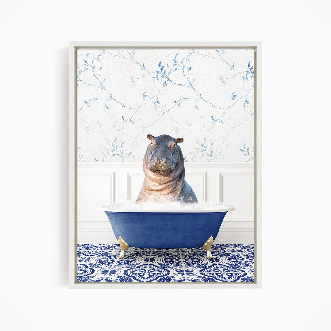 A hippopotamus sitting in a blue bathtub filled with water, surrounded by a patterned tile floor and a floral wallpaper background.
