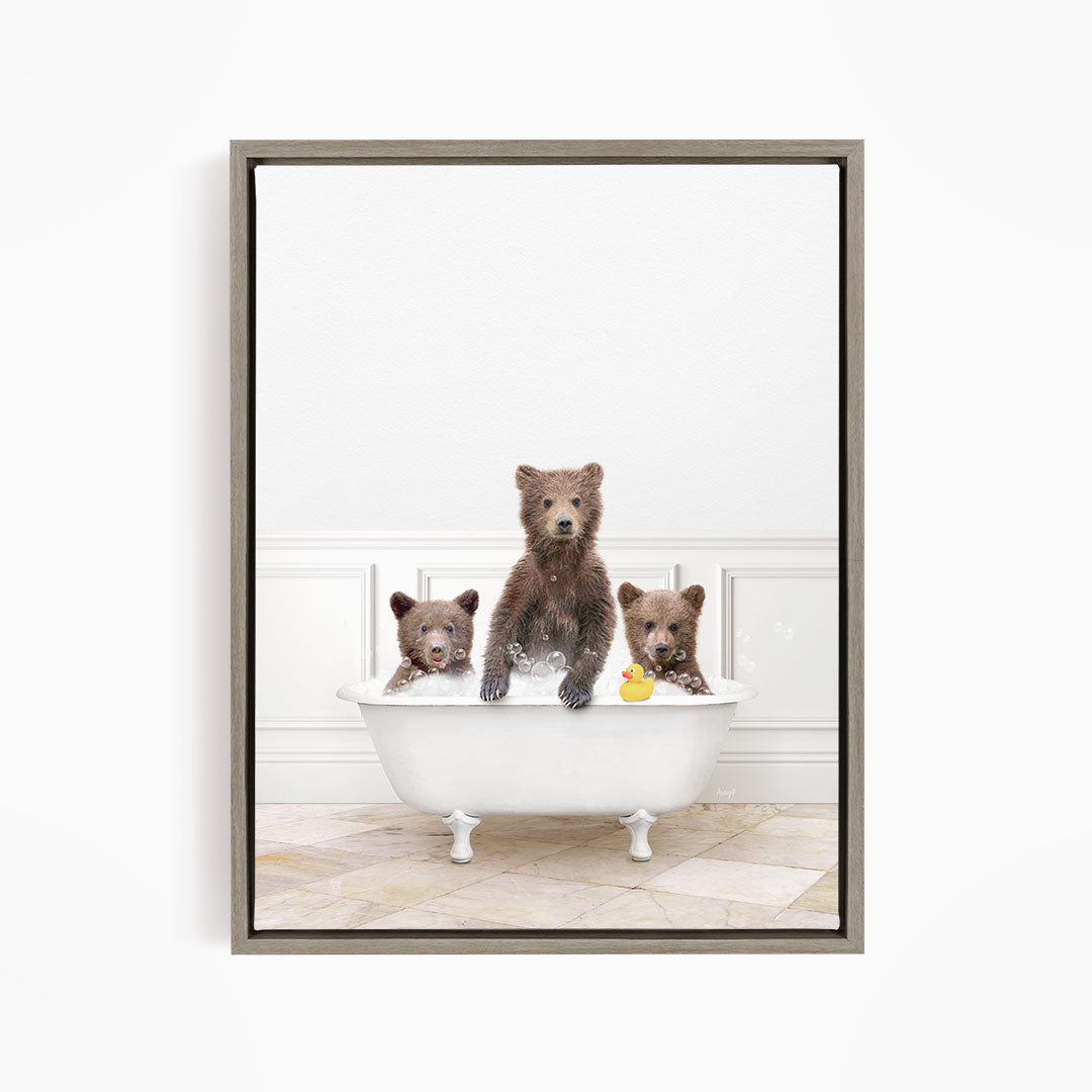 A framed image showing three brown bears sitting in a white bathtub, with a rubber duck floating in the water.