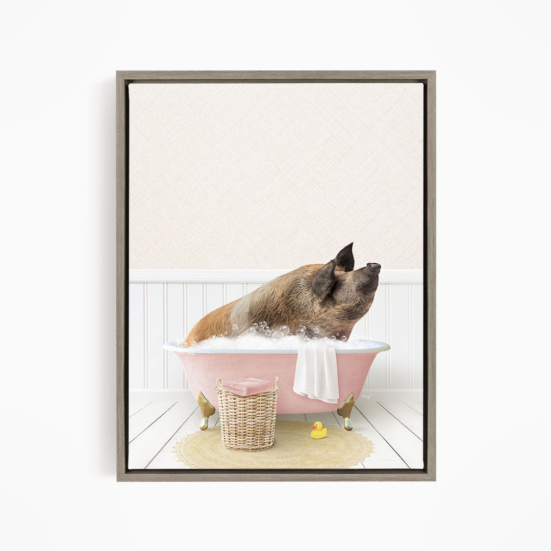 A brown pig sitting in a pink bathtub filled with bubbles, surrounded by a yellow rubber duck and a basket of bath toys.