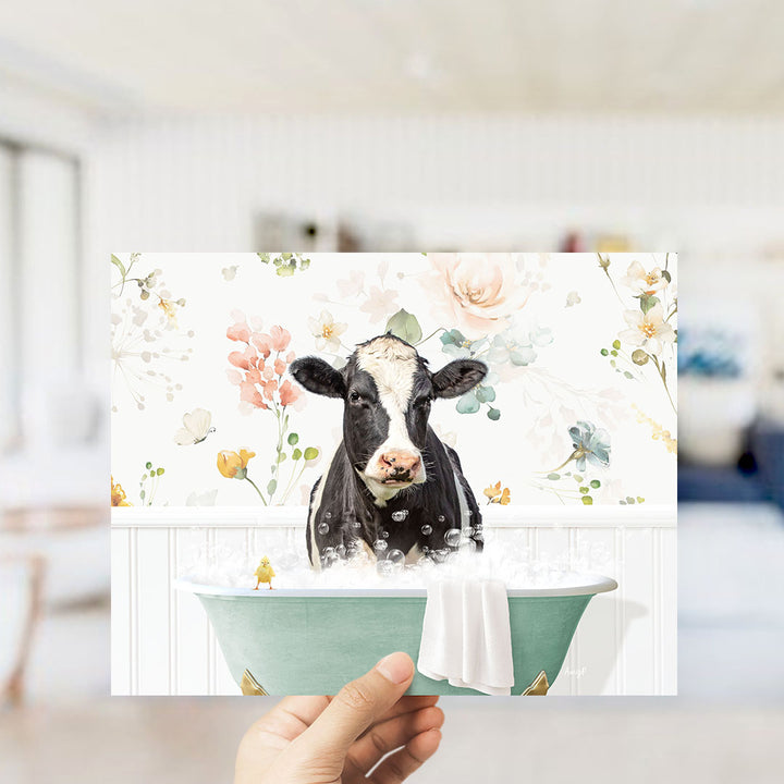 A black and white cow is sitting in a green bathtub filled with bubbles, surrounded by a floral pattern.
