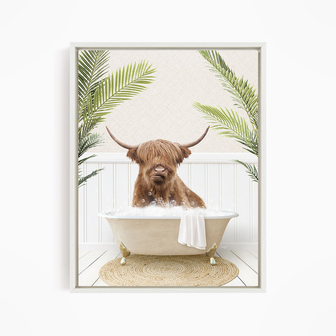 A brown cow with long horns is sitting in a white bathtub filled with bubbles, surrounded by green palm leaves.