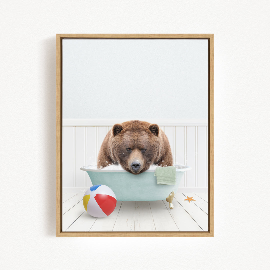 A brown bear is sitting in a bathtub filled with water, surrounded by a beach ball and a towel.