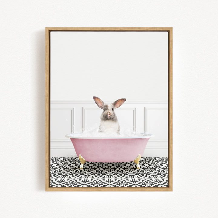 A gray and white rabbit sitting in a pink bathtub filled with water, surrounded by a black and white patterned floor.