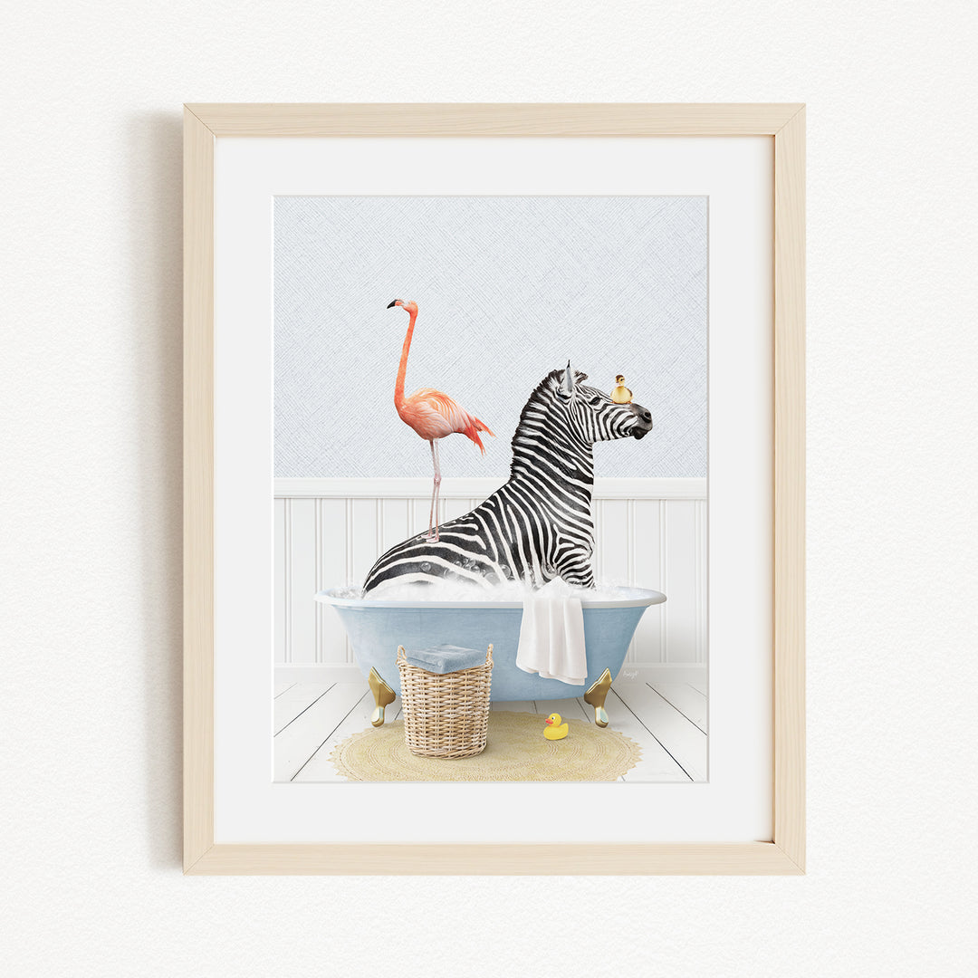 A framed image depicting a zebra sitting in a bathtub, with a pink flamingo standing on its back and a basket of rubber ducks nearby.