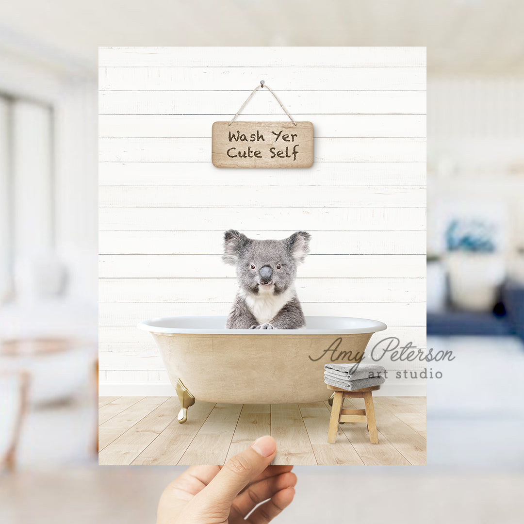 a hand holding a photo of a koala in a bathtub