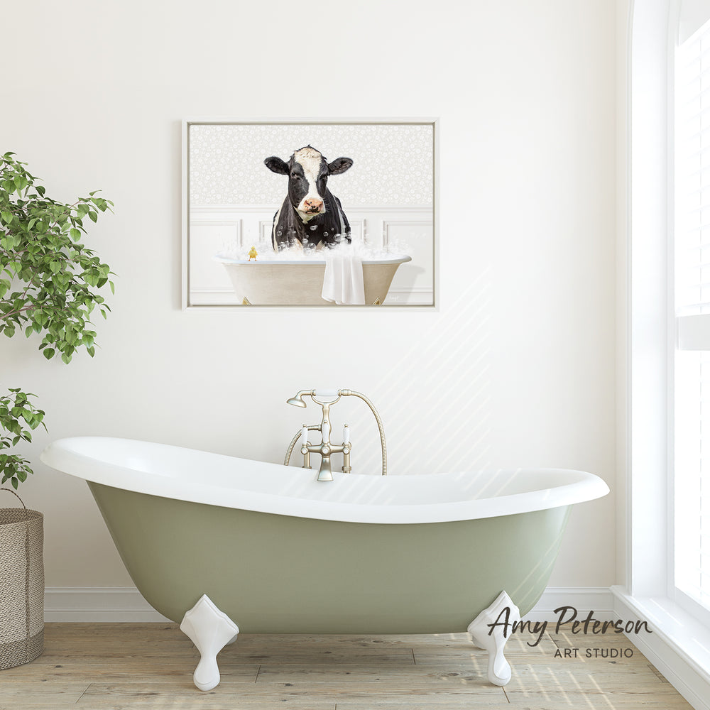 A framed image of a cow sitting in a bathtub is displayed on the wall above a green clawfoot bathtub in a bathroom.