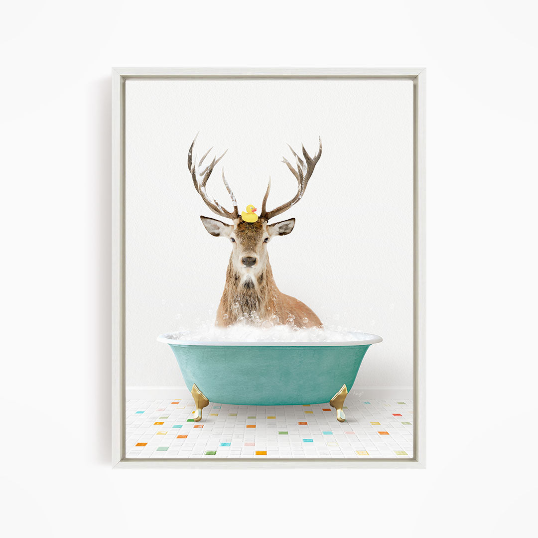 A deer with antlers is sitting in a green bathtub filled with bubbles, with a yellow rubber duck floating on its head.