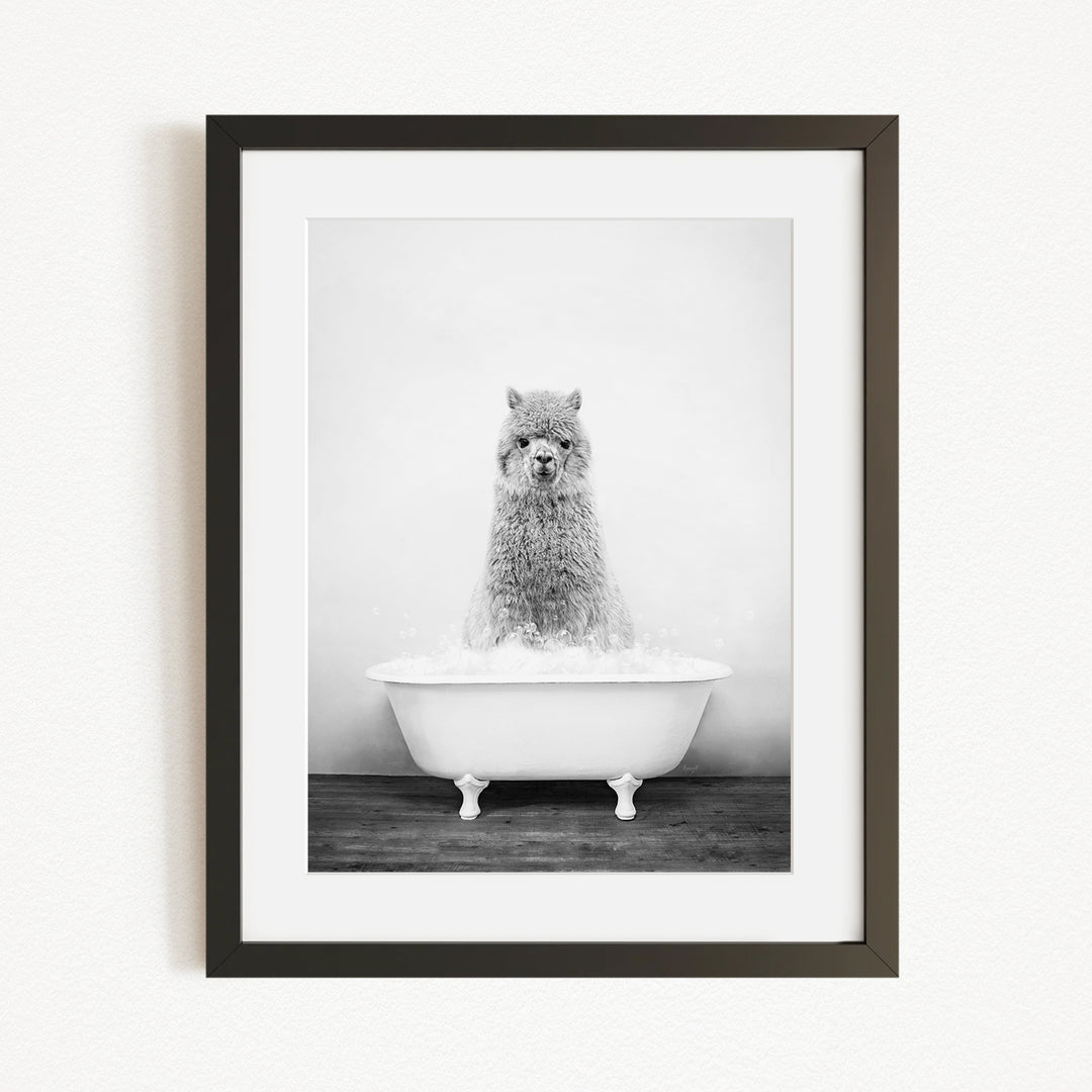 A black and white image of a fluffy, furry animal, possibly a dog or a cat, sitting in a white bathtub filled with water.