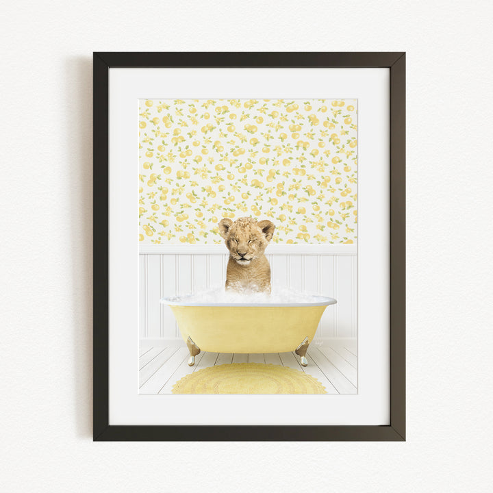 A young lion cub sitting in a yellow bathtub filled with water, surrounded by a yellow floral wallpaper.