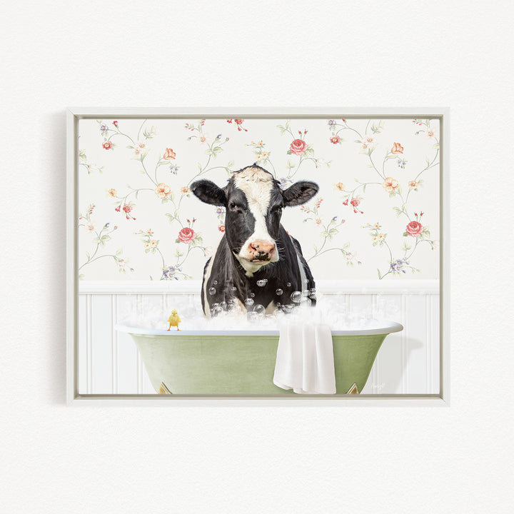 A black and white cow is sitting in a green bathtub filled with bubbles, with a yellow bird perched on the edge of the tub.