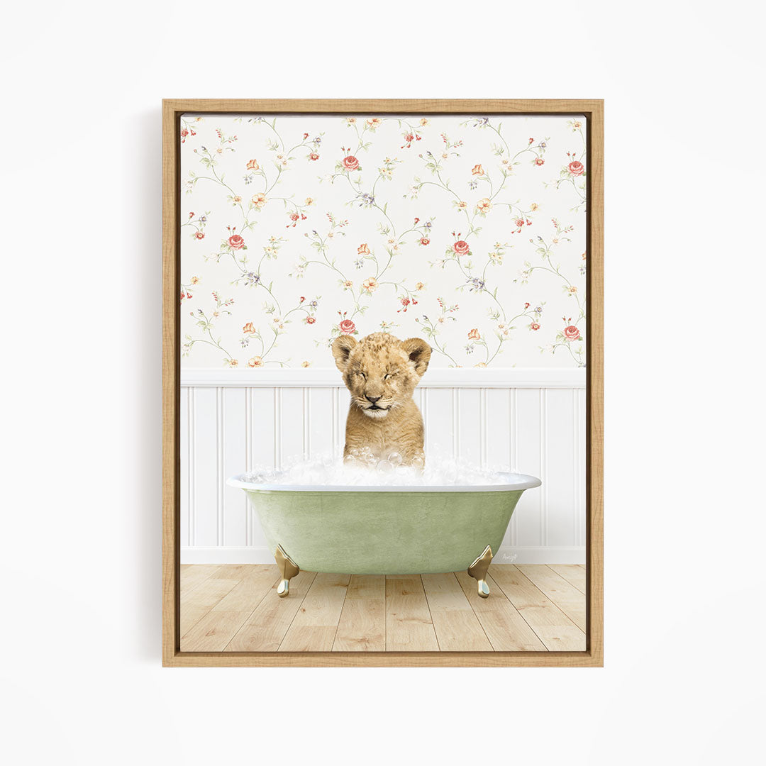 A young lion cub sitting in a green bathtub filled with water, with a floral wallpaper in the background.