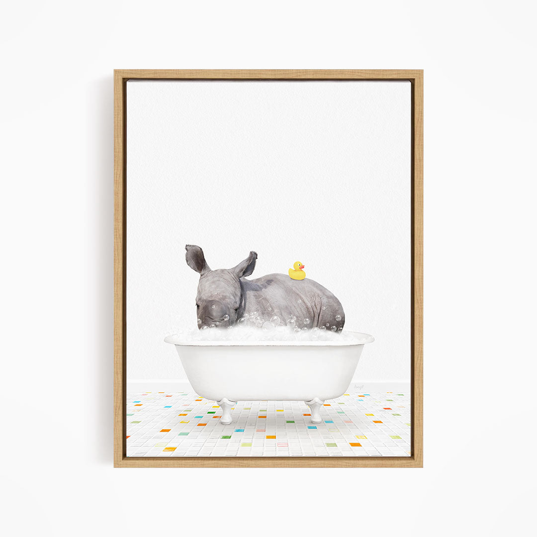 A rhinoceros is sitting in a white bathtub filled with water, with a yellow rubber duck floating on its back.