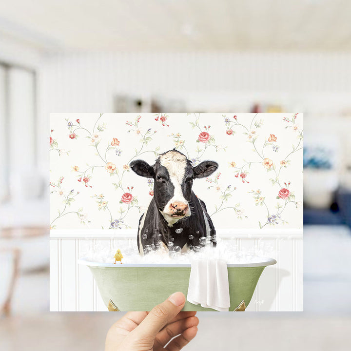 A black and white cow is sitting in a green bathtub filled with bubbles, with a yellow bird perched on the edge of the tub.