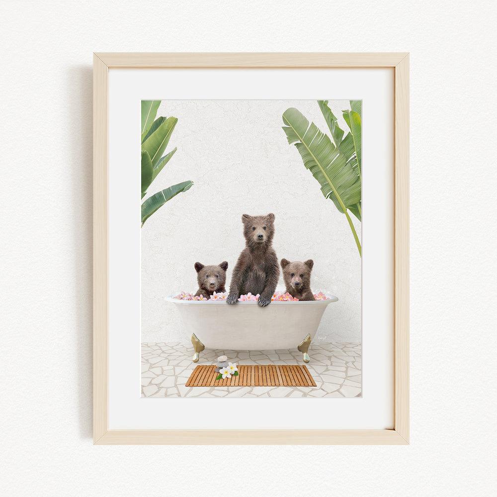 A framed image depicting three bears sitting in a bathtub filled with flowers, surrounded by tropical plants.