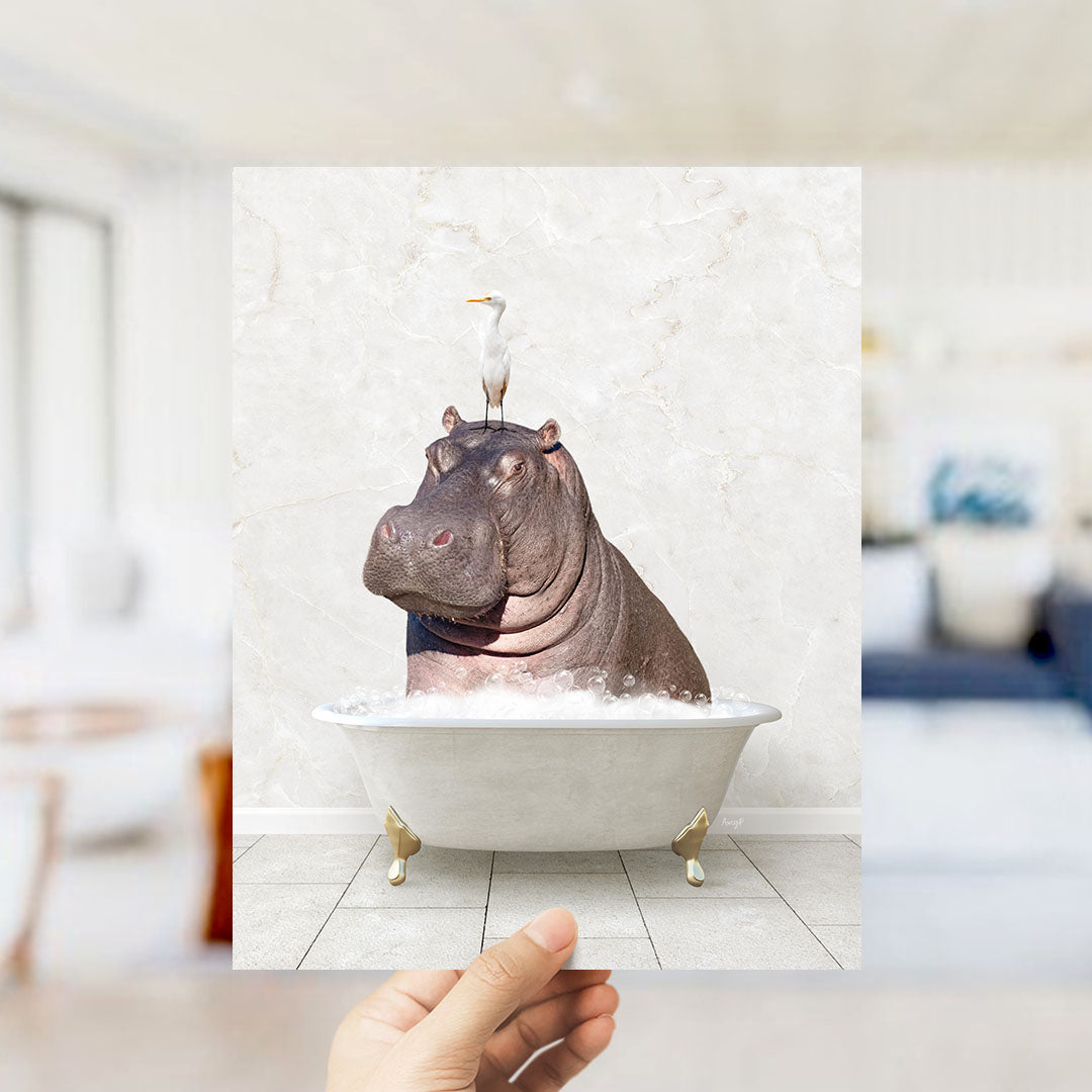 A hand holds up a framed image of a hippopotamus sitting in a bathtub, with a seagull perched on its head.