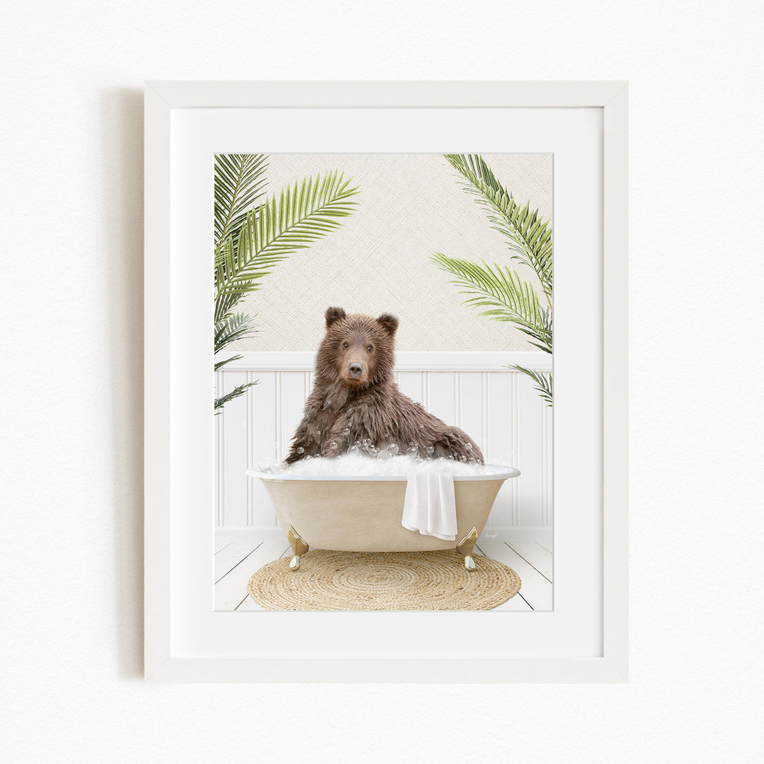 A brown bear sitting in a bathtub filled with bubbles, surrounded by green palm leaves.