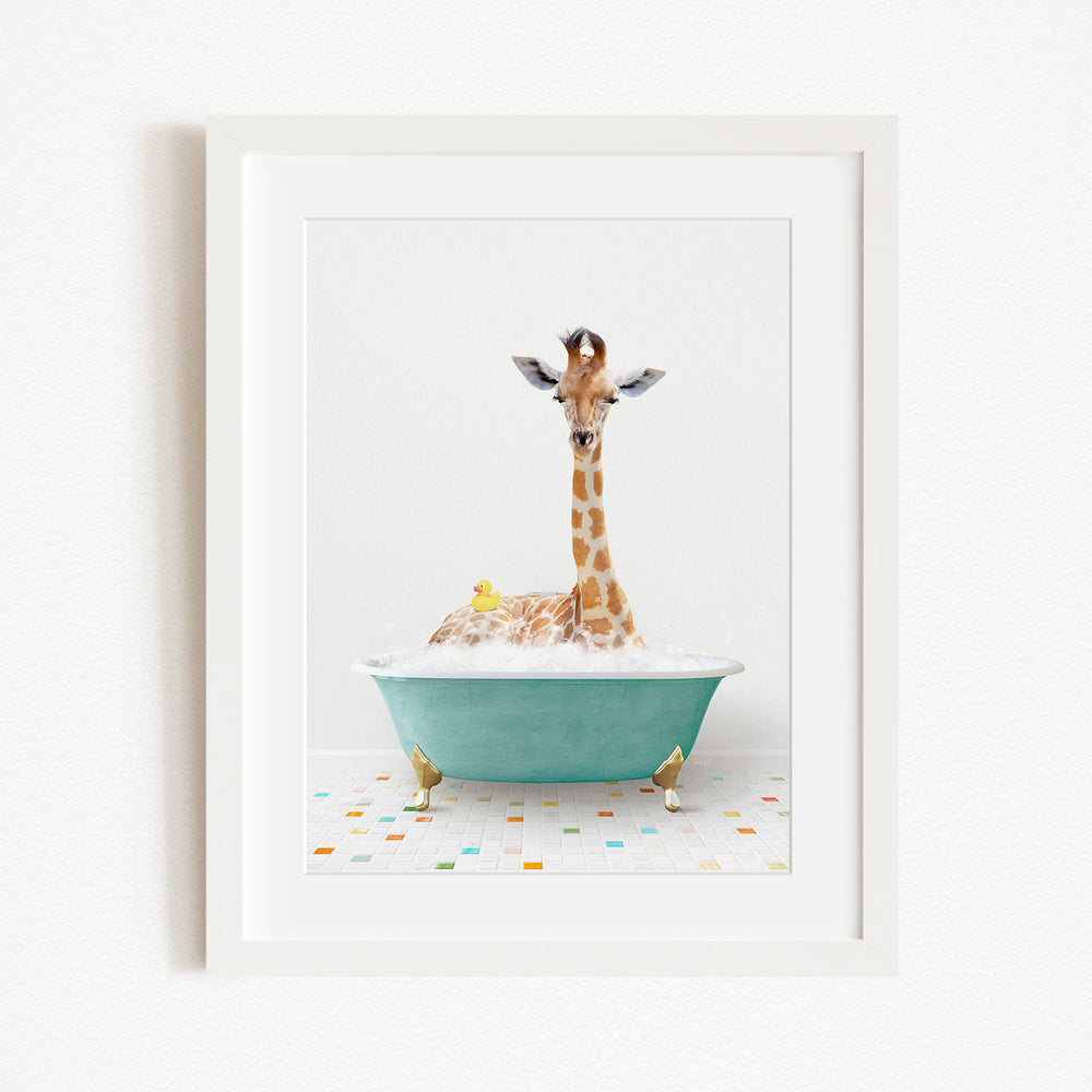 A giraffe is sitting in a green bathtub filled with bubbles, surrounded by a yellow rubber duck and a small bird.