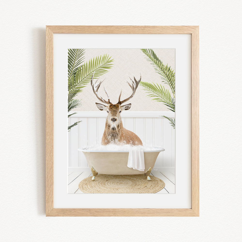A deer with antlers is sitting in a bathtub filled with bubbles, surrounded by green plants.