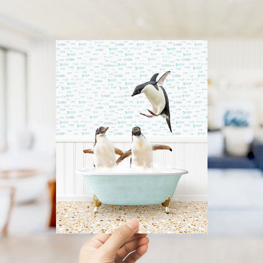 A hand holds up a collage of two images depicting penguins in a bathtub, with one penguin flying above the other.