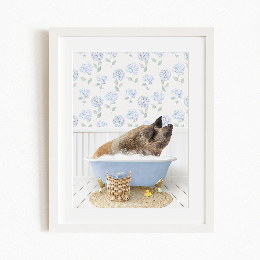 A brown dog is sitting in a blue bathtub filled with bubbles, surrounded by a white floral wallpaper and a basket of rubber ducks.