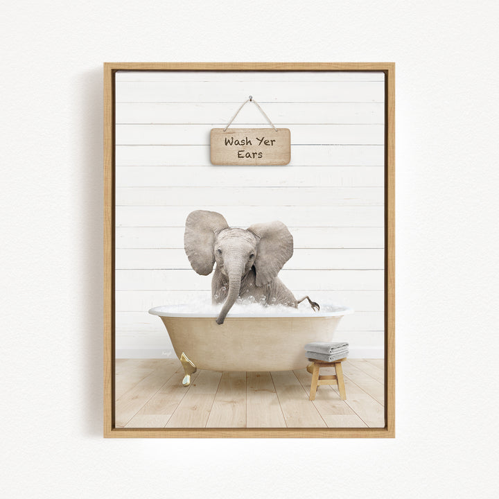 A framed image depicting an elephant sitting in a bathtub, with a sign above that reads "Wash Your Ears".