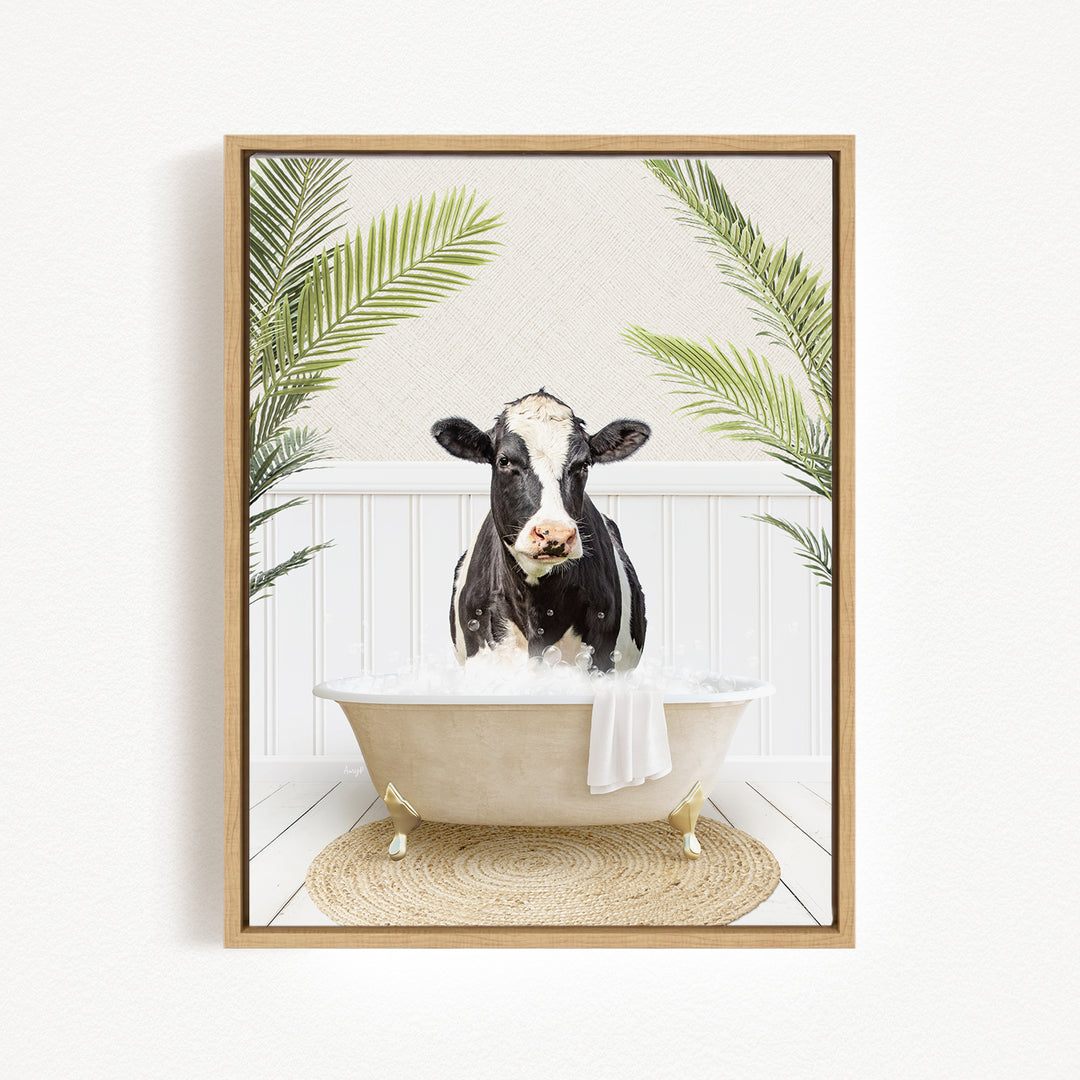 A black and white cow is sitting in a bathtub filled with water, surrounded by green palm leaves.