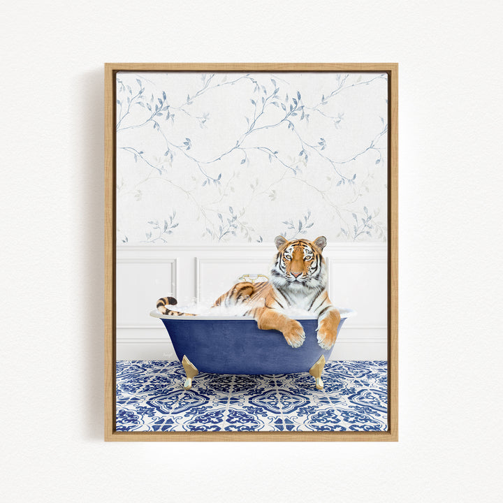 A tiger is sitting in a blue bathtub, surrounded by a blue and white patterned floor and a white wall with a floral pattern.