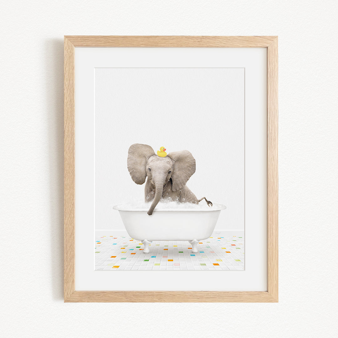 A gray elephant is sitting in a white bathtub, with a yellow rubber duck floating on its head.
