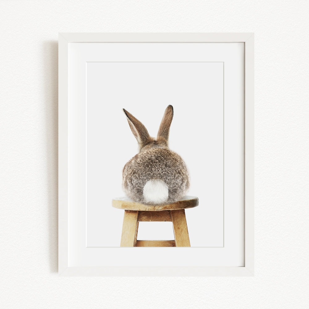 A picture of a rabbit sitting on a wooden stool.