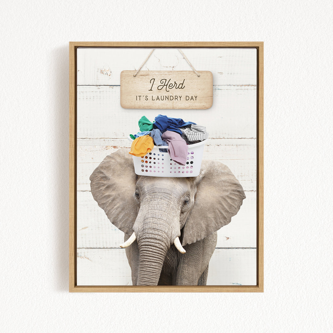 A framed image of an elephant wearing a basket of laundry, with a sign above it that says "It's laundry day".