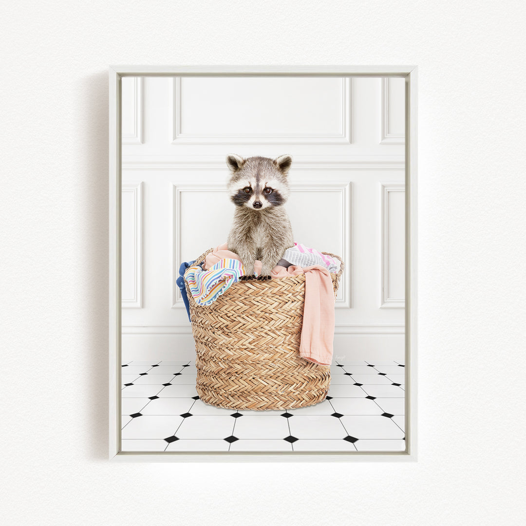 A raccoon sitting in a woven laundry basket filled with clothes.