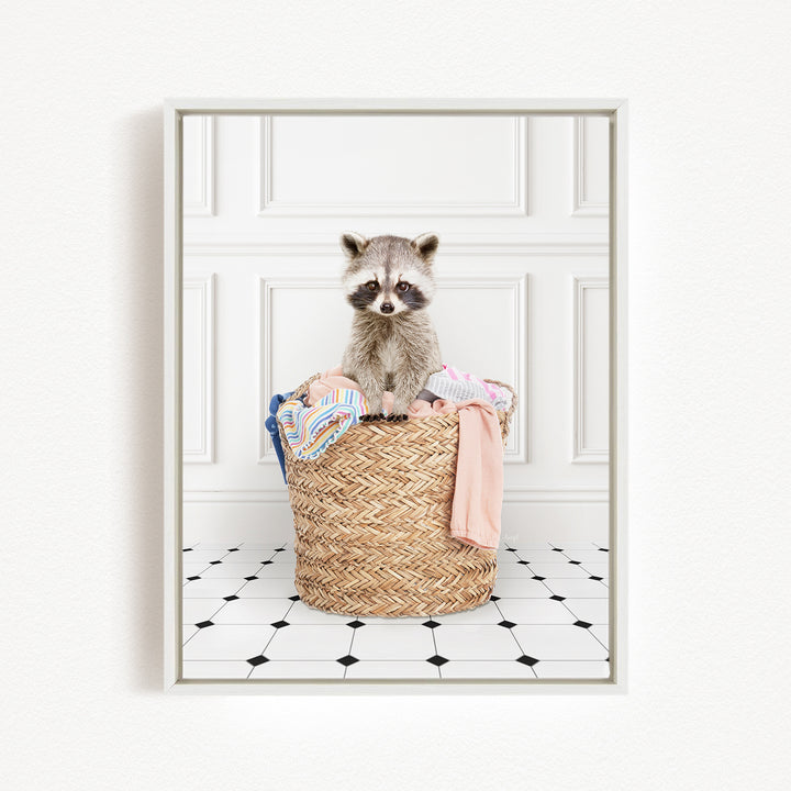 A raccoon sitting in a woven laundry basket filled with clothes.