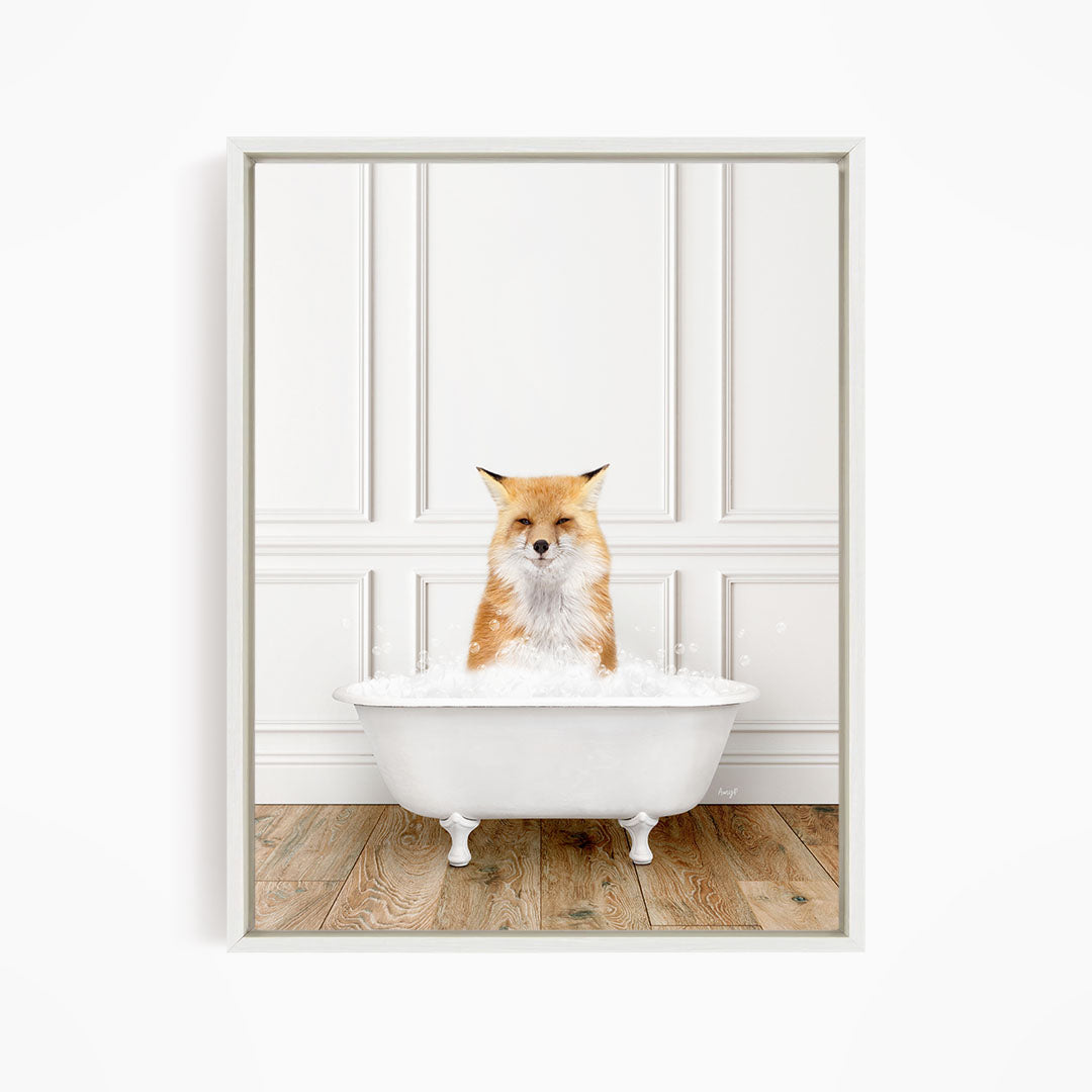 A red fox is sitting in a white bathtub filled with bubbles, looking directly at the camera.